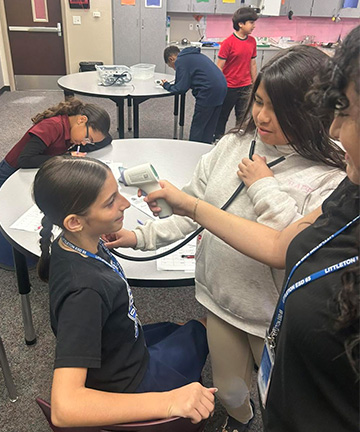 Two students pretending to do a medical exam on another student