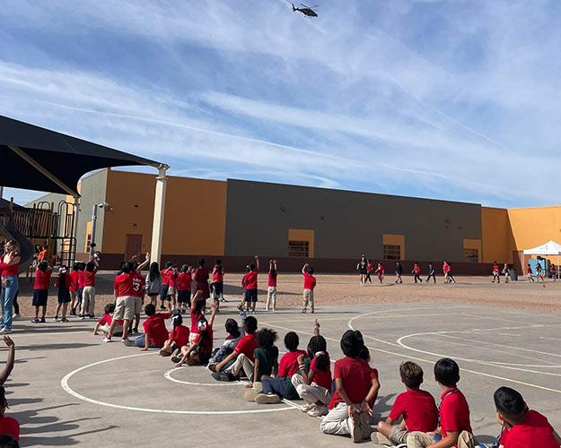 Students outside in the playground watching a helicopter fly overhead