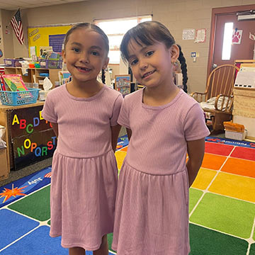 Two girls wearing matching pink dresses