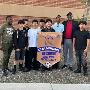 Boys soccer team holding up a championship banner for 2026