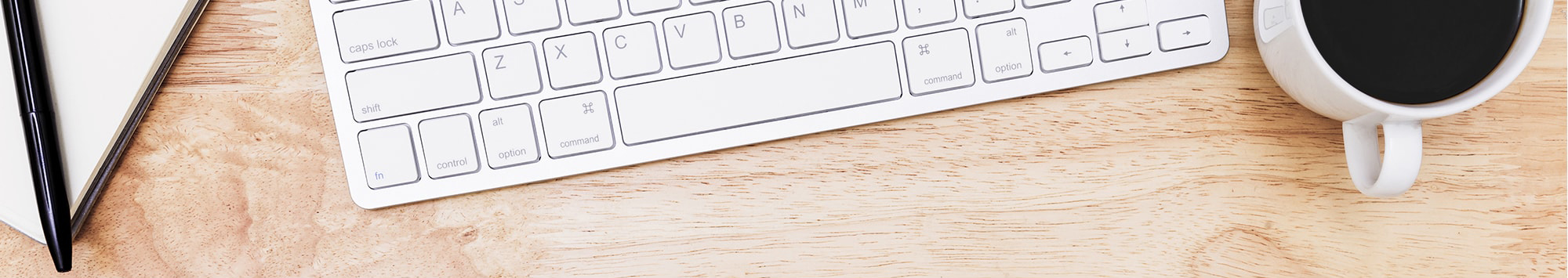 computer keyboard, cup of coffee, pen and paper