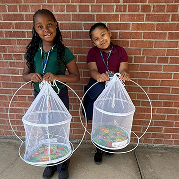 Two girls holding butterfly containers