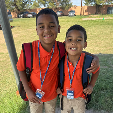 Two happy boys outside wearing name badges