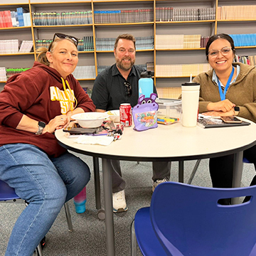 Three staff members sitting at a round table