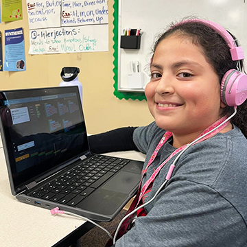 Student looking up from computer to smile for the camera