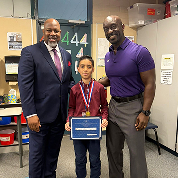Student receiving an award next to principal and superintendent