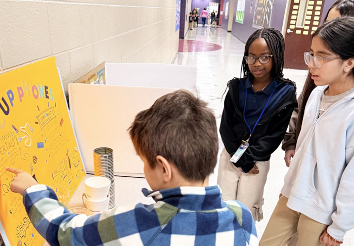 Students looking at a science project poster