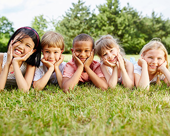 Group of diverse elementary students outside on the grass