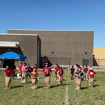 Students enjoying a potato sack race outside on campus
