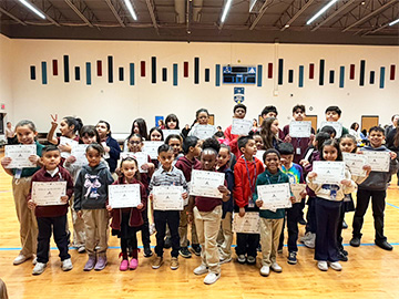 Group of happy student holding up certificates in the school gym