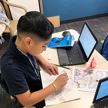 Student working on a project from his desk in the classroom