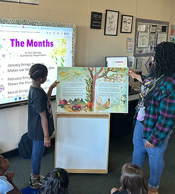 Students watching a student and staff read a book