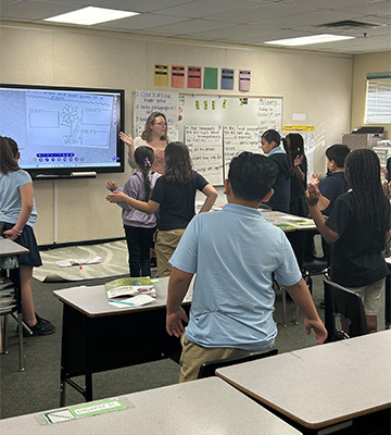 Students standing and watching a presentation on a screen