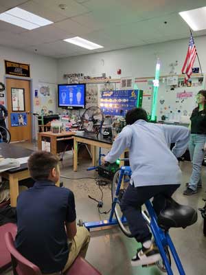 Students watching staff run a bicycle to create electricity