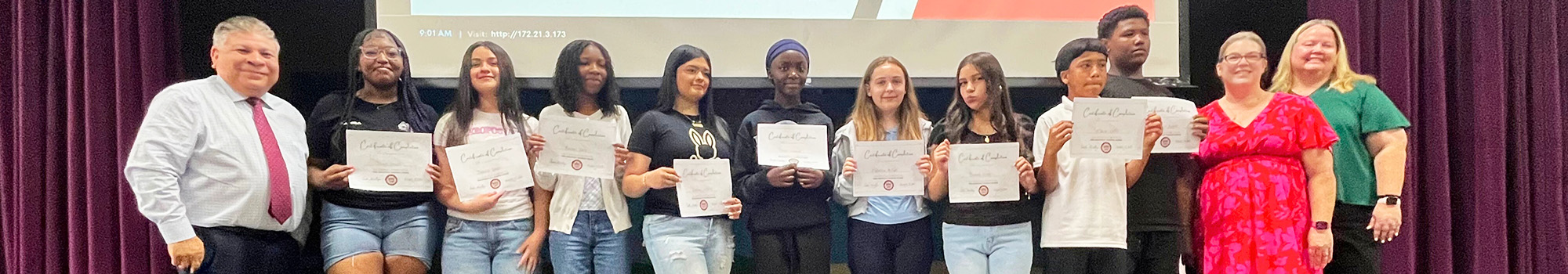 Students on the stage holding up certificates