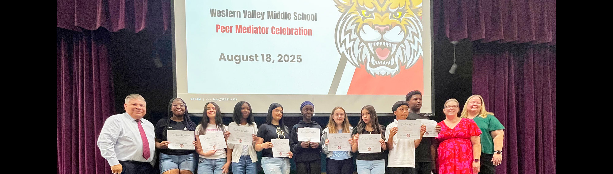Group of happy students and teachers on stage under Western Valley Middle School Peer Mediator Celebration August 18, 2025 banner