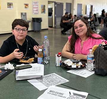Student and women sitting at a table in the cafeteria