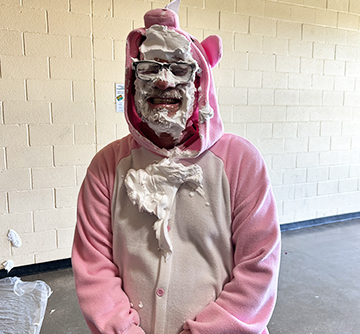 Adults in a pig costume with pie in the face