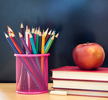 Colored pencils next to apple on books