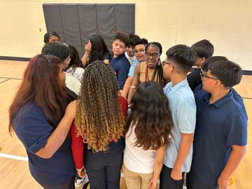 students in a huddle with their teacher