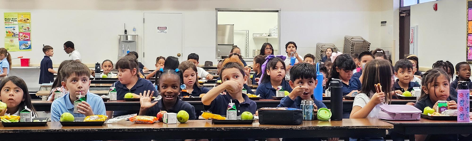 Happy elementary students enjoying lunch in the classroom