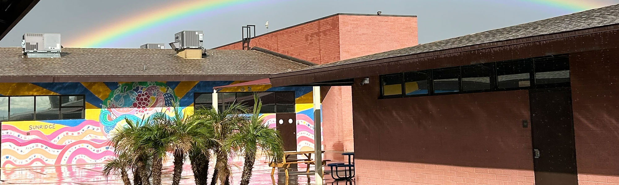 View of school building with a rainbow up in the sky