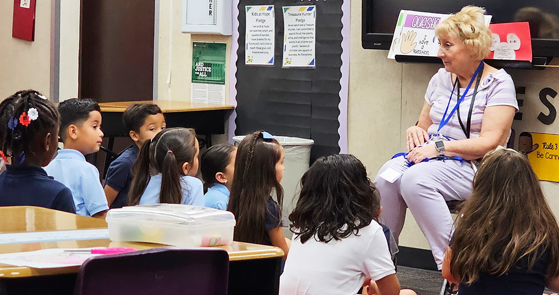Students sitting around a teacher in a classroom