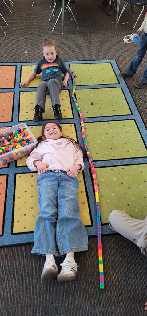 Two students laying on the classroom carpets