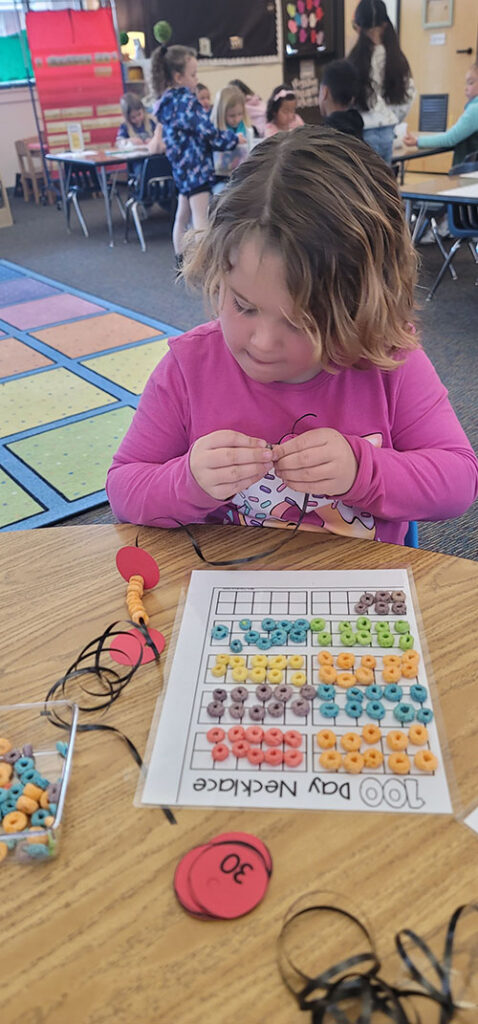 Student in pink counting items from her desk