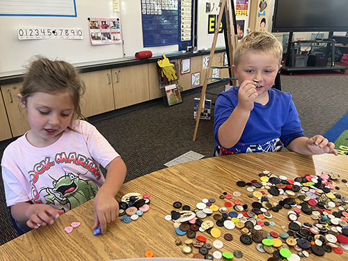 Two students sorting colorful buttons at a table