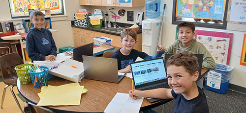 Happy third grade students working on a project in the classroom