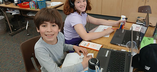 Two students looking up to smile for the camera