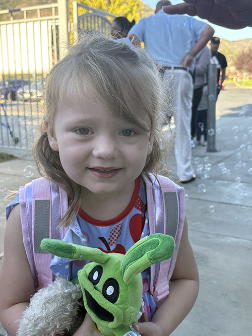 Happy elementary student holding a green toy
