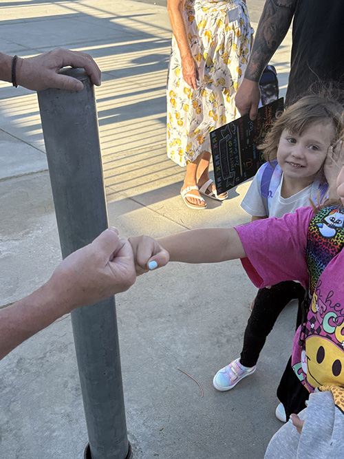 Student giving a fist bump to an adult
