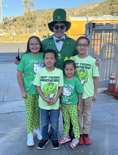 Principal McNelis dressed as a leprechaun with a group of happy students