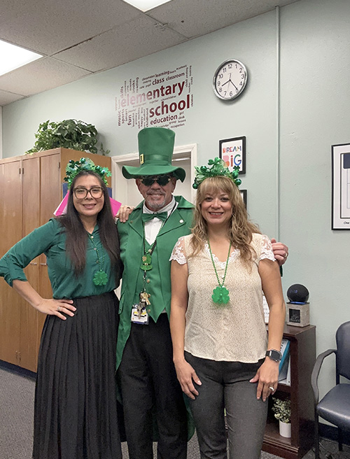 Principal McNelis dressed as a leprechaun with two staff members