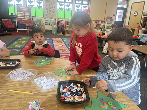TK students at a table making Chicka Chicka alphabet trees together