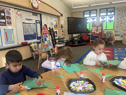 TK students cutting green paper to make Chicka Chicka alphabet trees