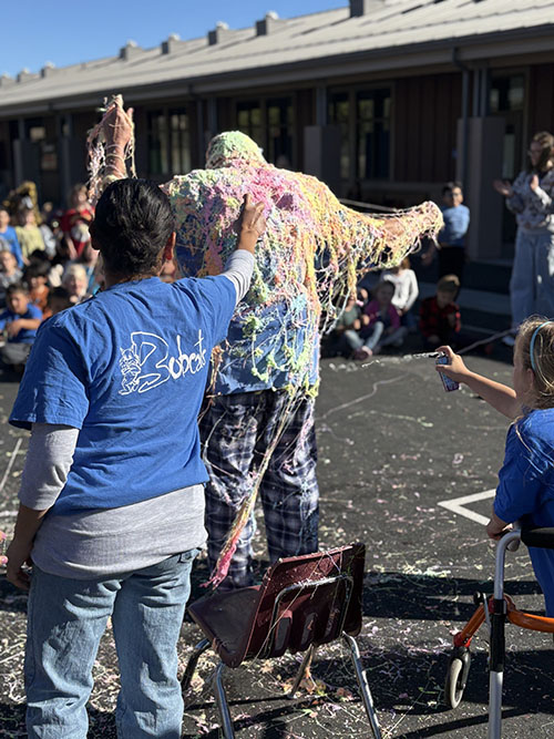 Students spraying Silly String on principal outside
