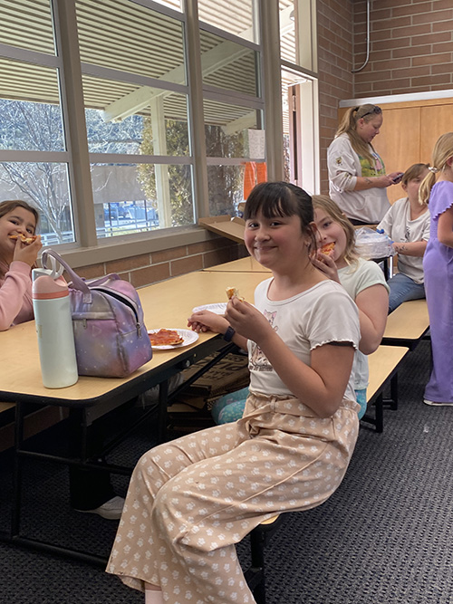 Girls eating pizza and smiling for the camera