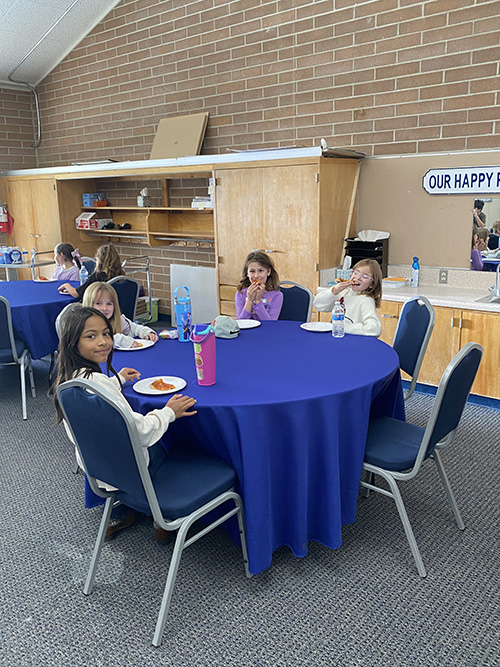 Students sitting at a round table to eat pizza