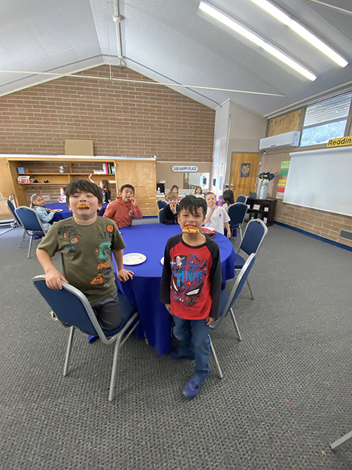 Students posing for a picture while enjoying pizza