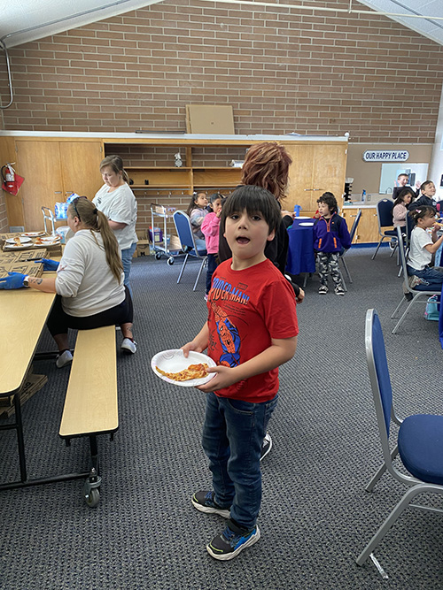 Student in red t-shirt holding a plate with pizza