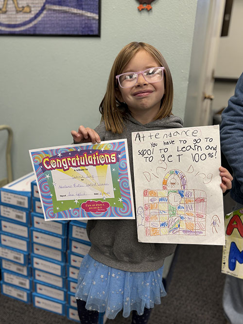 Student holding up award certificate and poster