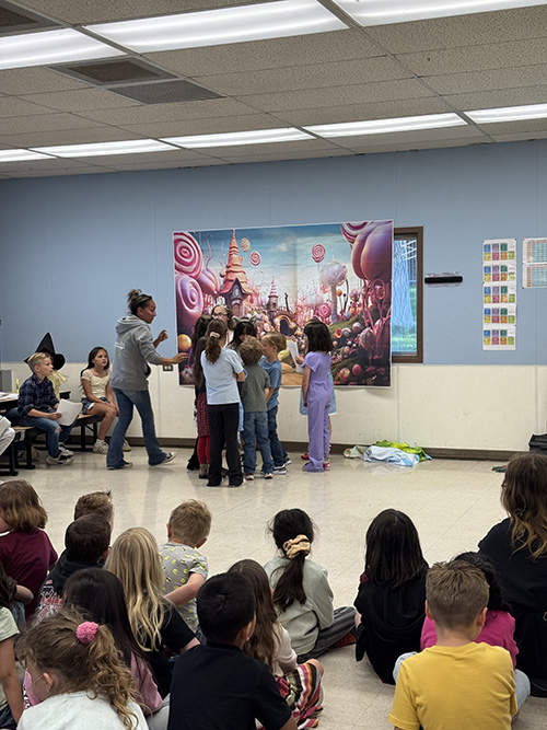 Students performing The Wizard of Oz for classmates in a multi-purpose room