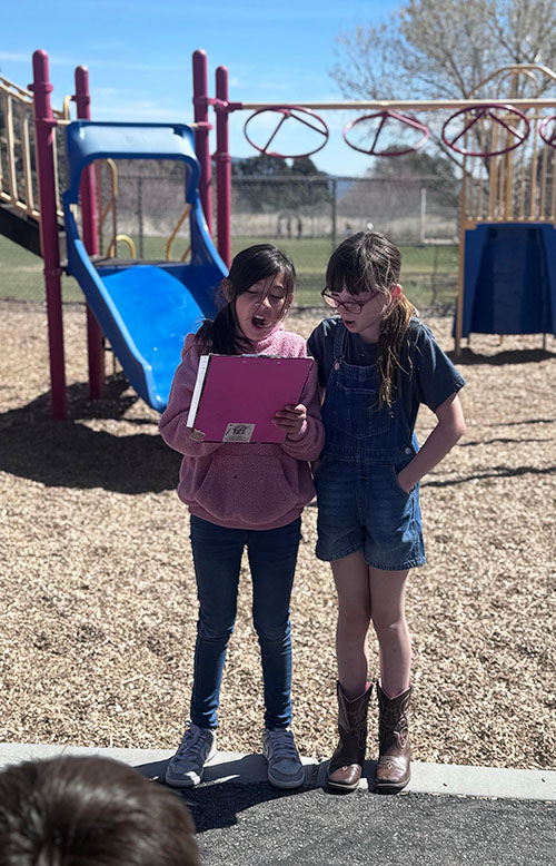 Two girls reading from a clipboard