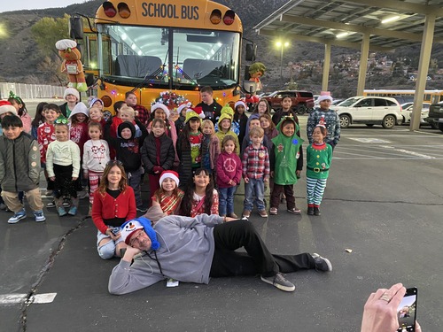 Group of student elves and principal in front of school bus