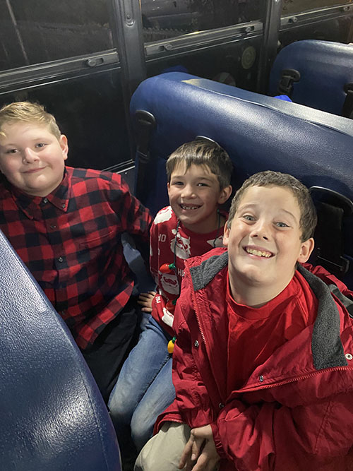 Three happy boys sitting together on a bus