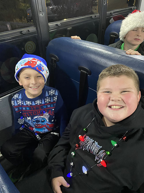 Two spirited student elves smiling on a bus