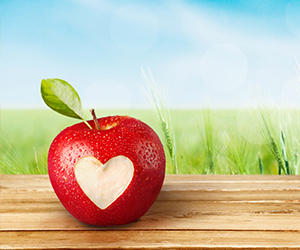 Red apple with heart-shaped bite on table